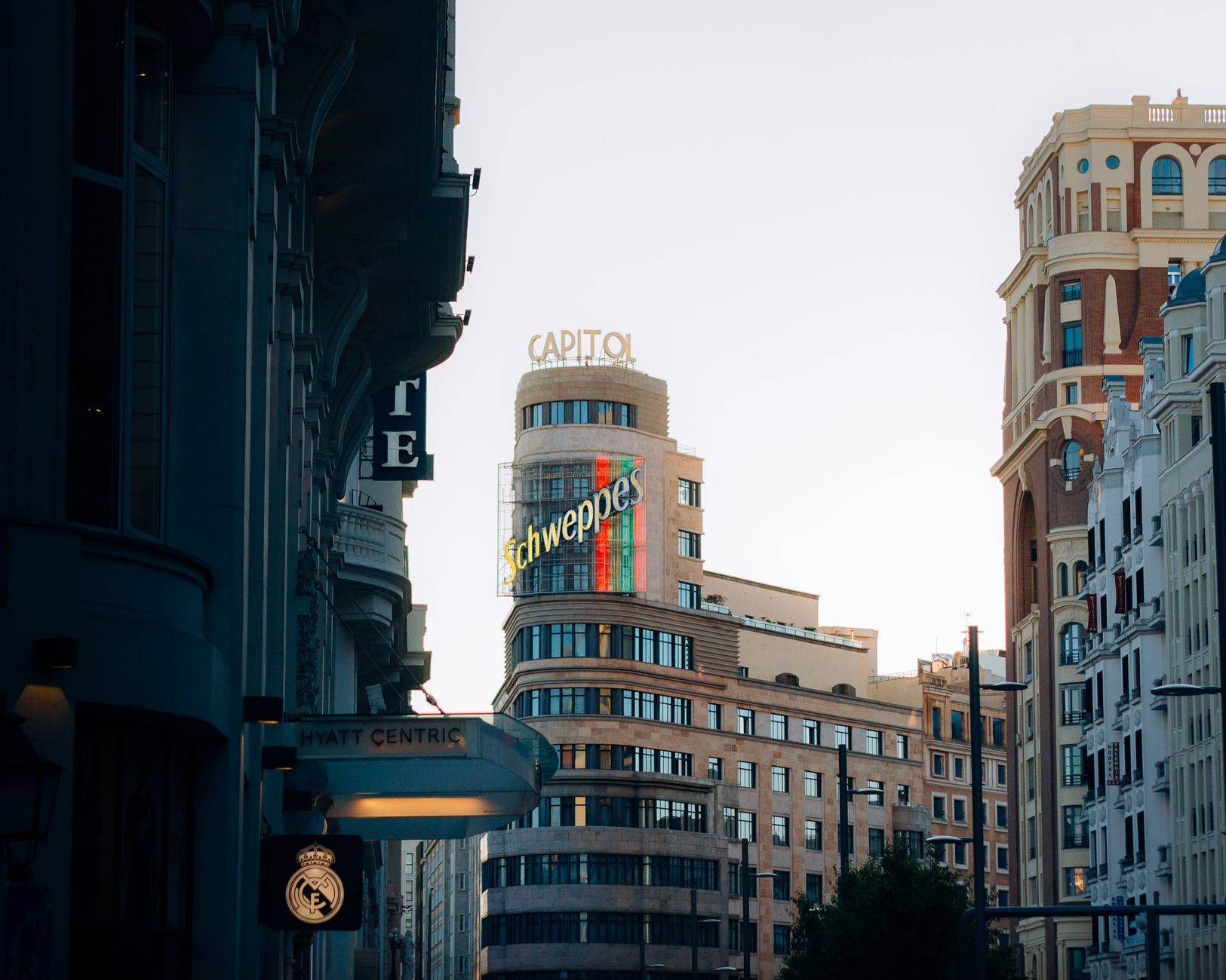 Admire the famous Schweppes sign on the Capitol building in Madrid during sunset.