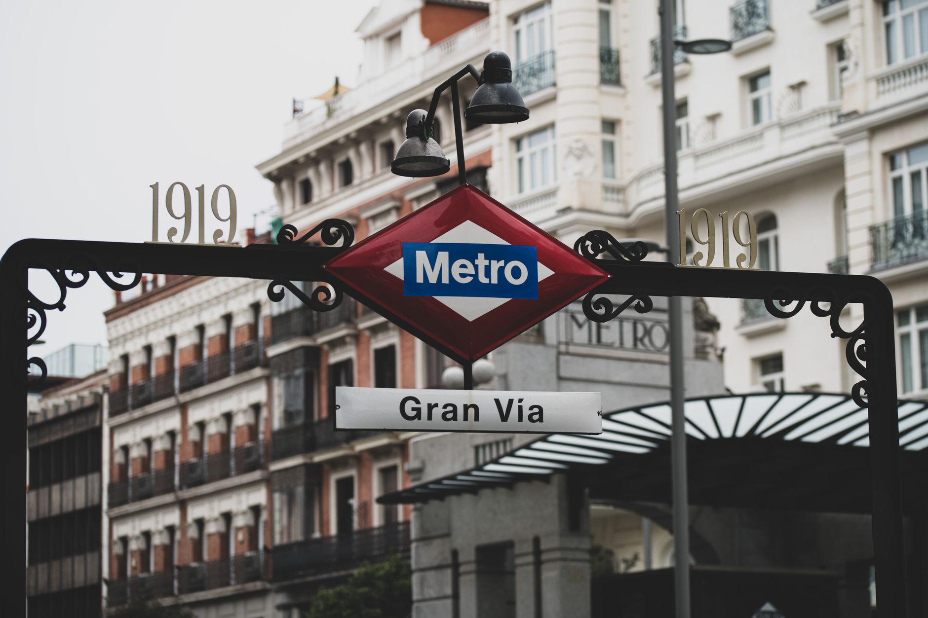 Classic view of Gran Via Metro entrance surrounded by historic architecture in Madrid.