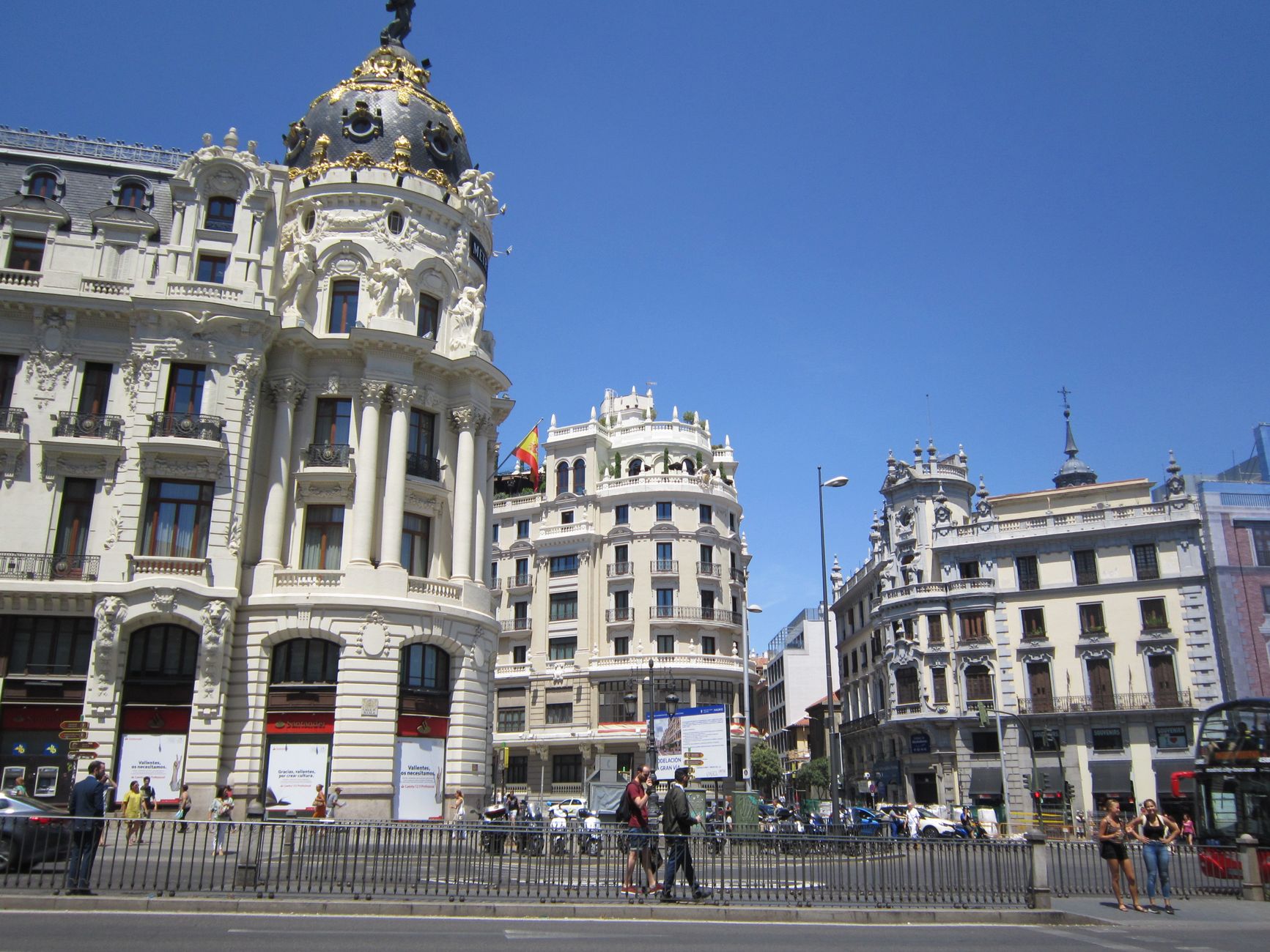 Vibrant street view of Gran Vía in Madrid, showcasing iconic architecture under a clear summer sky.