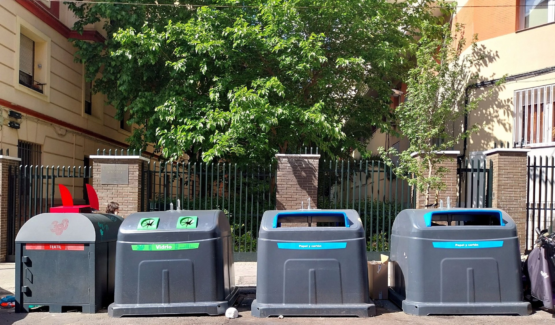 A row of Madrid street containers for textiles, glass, and paper and card