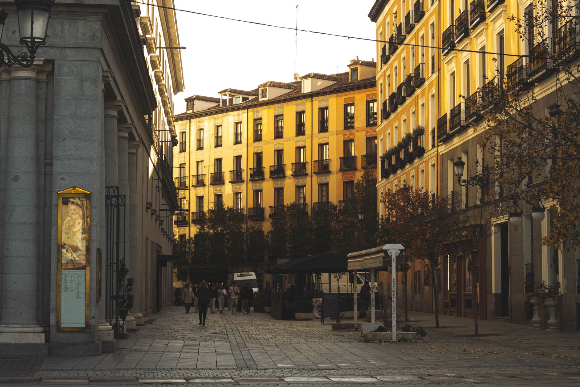 Warm sunset over a classic Madrid street lined with historic buildings and trees, capturing urban charm