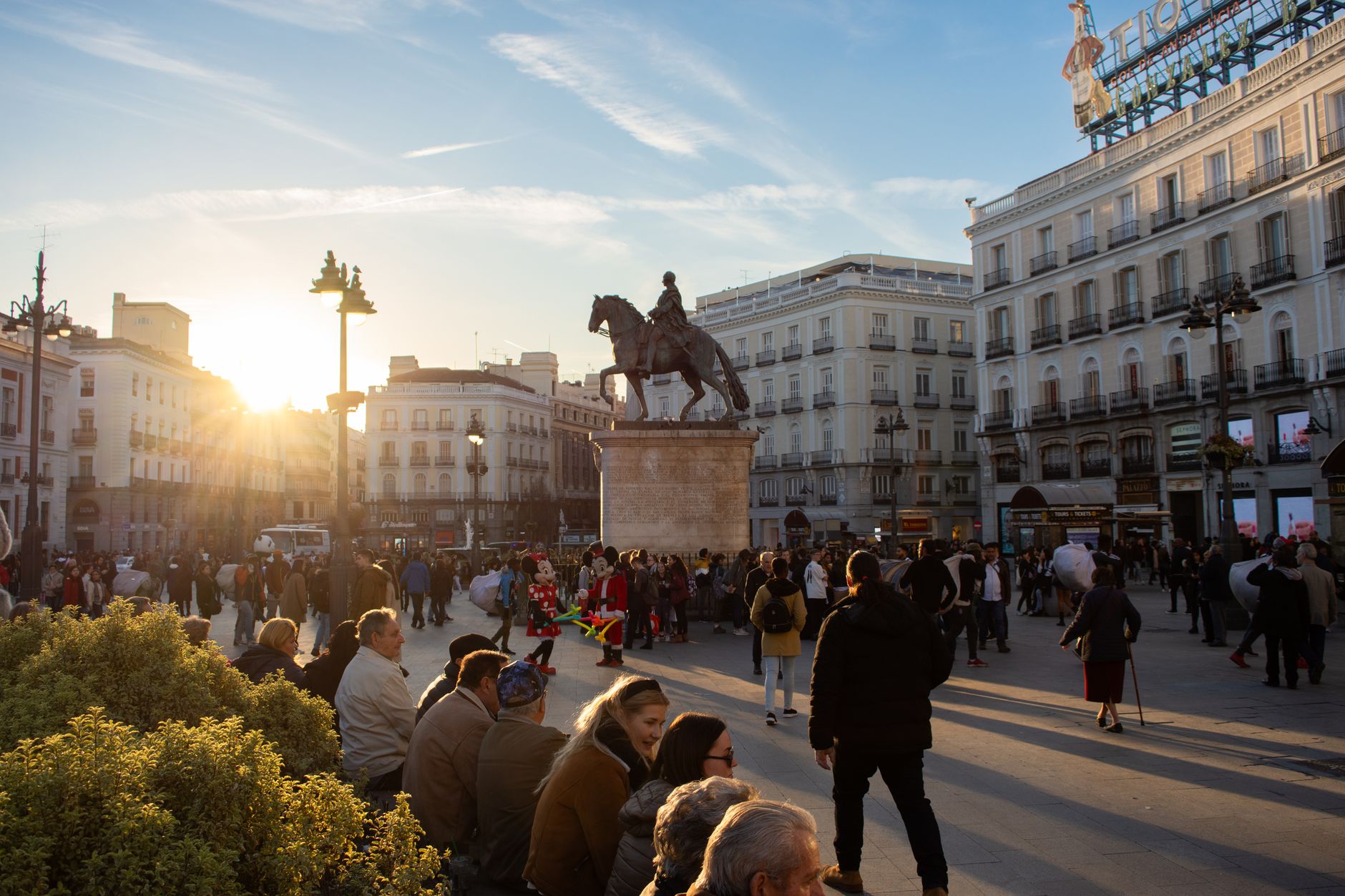 Tourists and locals gather at Puerta del Sol in Madrid during sunset, with the statue of King Charles III in view. — illustrating Madrid’s Main Railway Stations, and What Each One