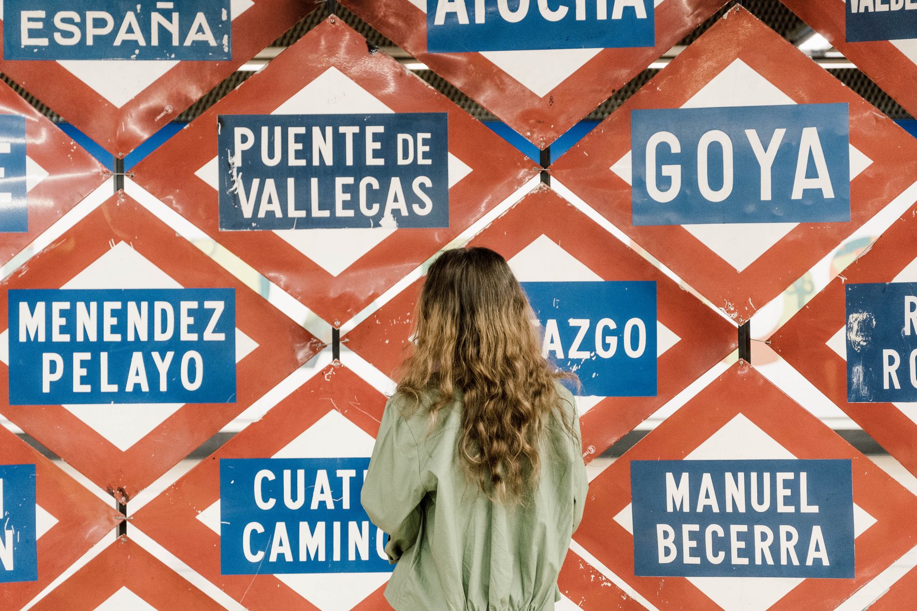 A woman observing multiple metro station signs in Madrid, Spain, showcasing urban exploration. — illustrating How Does the Madrid Metro Fare System Work?