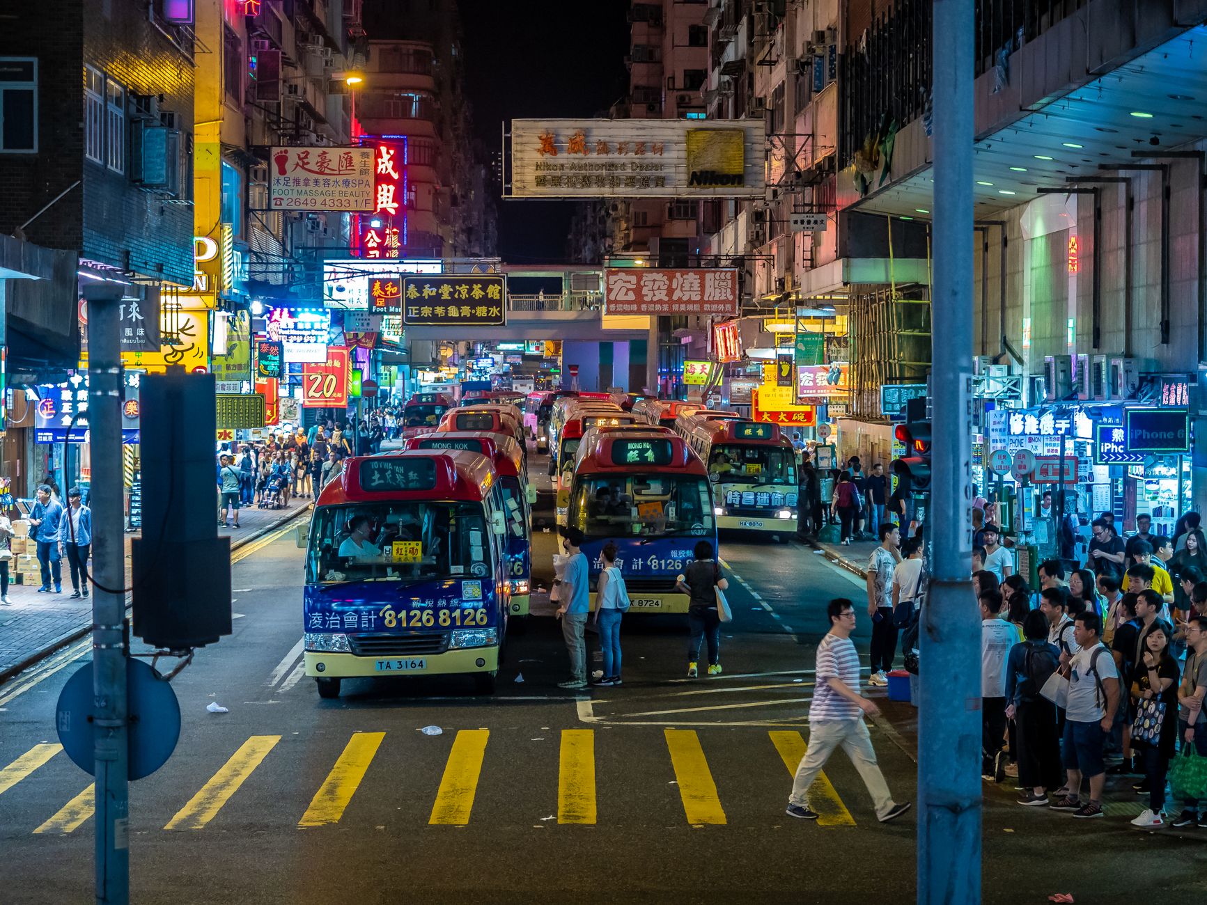 Vibrant night view of Hong Kong's bustling city streets filled with buses and pedestrians. — illustrating What Are Madrid’s Night Buses? The Búho Network Explained