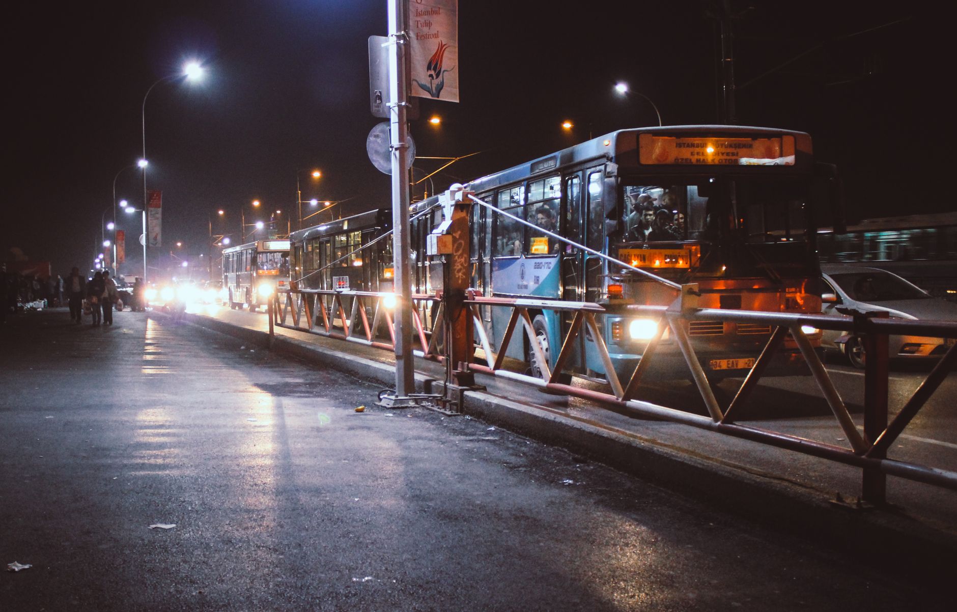 Urban night scene with buses and traffic along a city street.