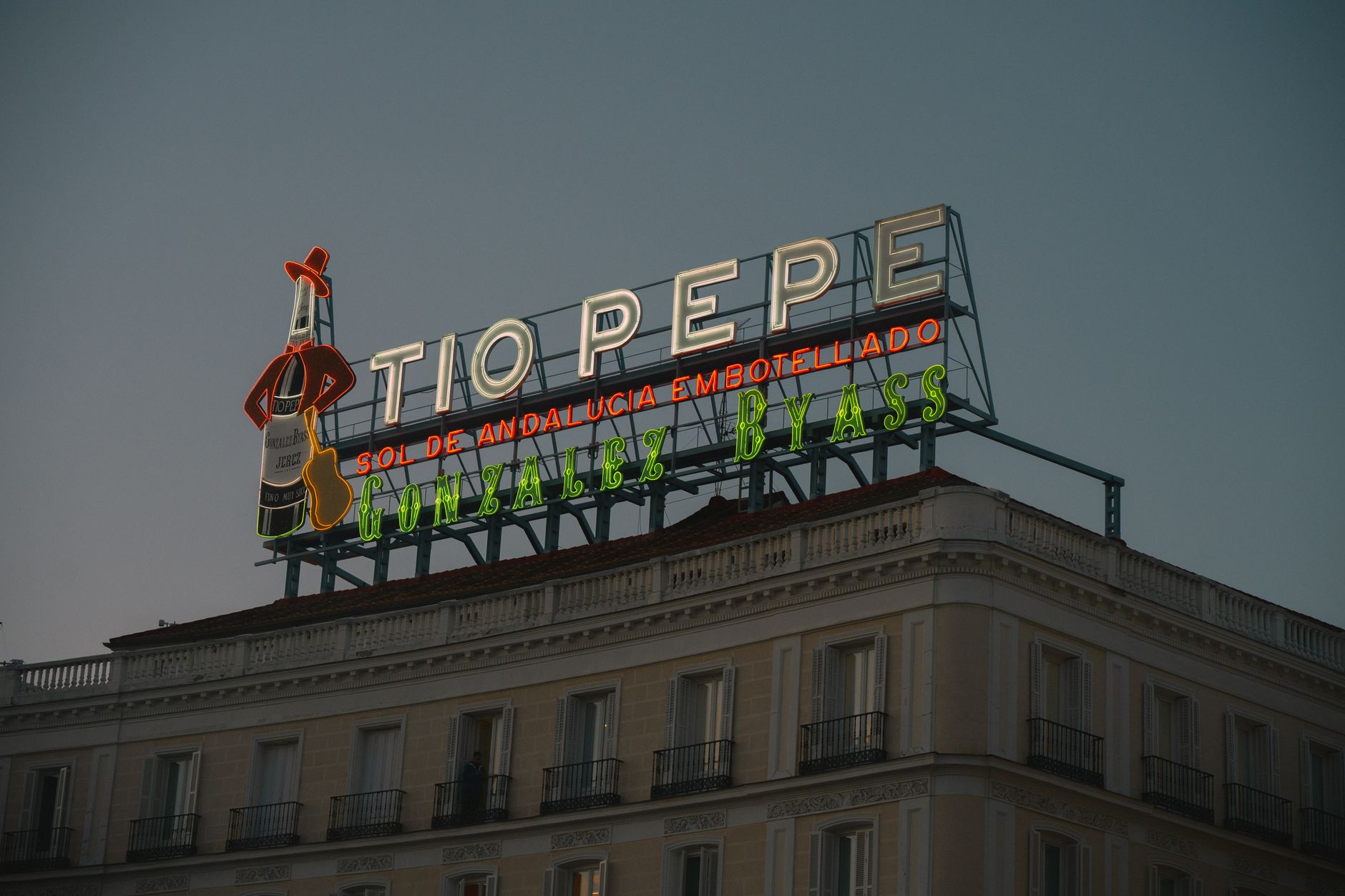 Neon Tio Pepe sign glowing at dusk in downtown Madrid's Puerta del Sol. — illustrating How Taxis and Ride-Hailing Work in Madrid: A Clear Guide