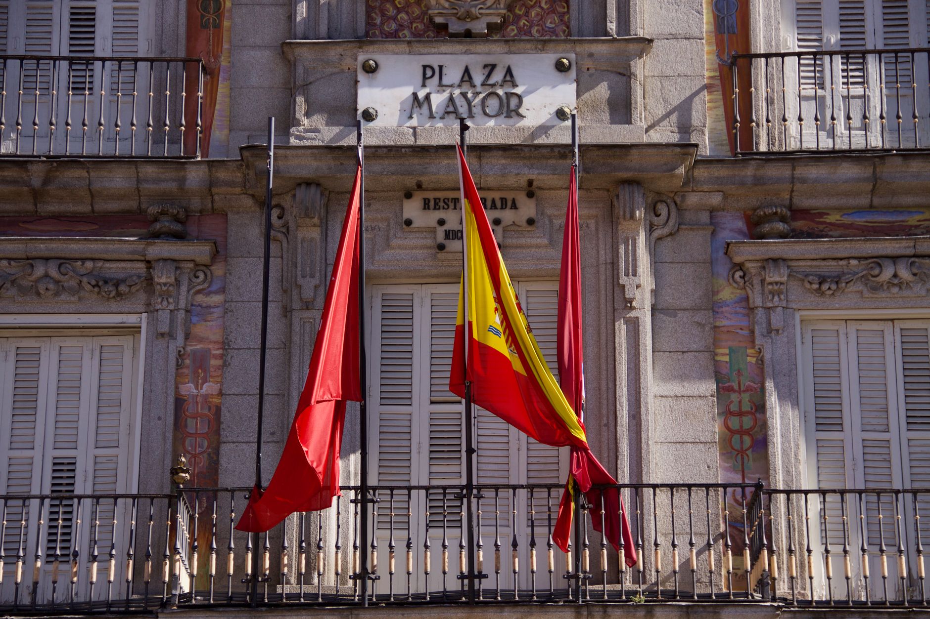 Detailed view of Plaza Mayor's facade with flags in Madrid, Spain, highlighting classic architecture. — illustrating What Is the Paseo del Arte Pass? Madrid’s Museum Ticket