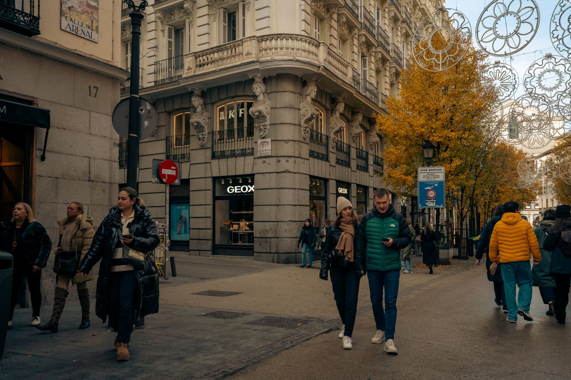 Street scene in Madrid's Calle del Arenal with autumn trees, shoppers, and European architecture. — illustrating How Do You Plan Around a Sunday in Madrid? A Guide