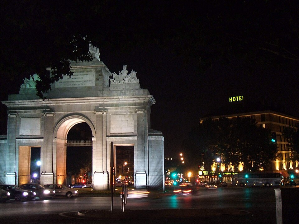 The Puerta de Toledo lit at night with traffic passing