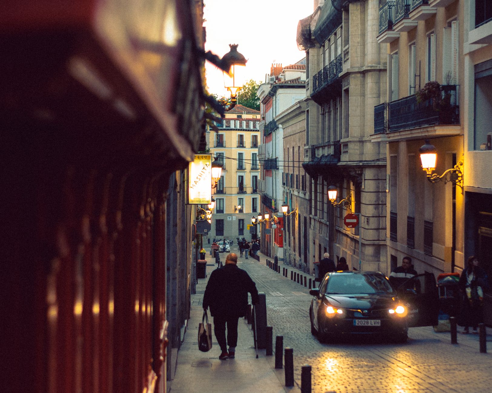 A man walks through cobblestone streets of Madrid at twilight, capturing urban life's essence. — illustrating Spanish Meal Times in Madrid: How They Reshape a Day