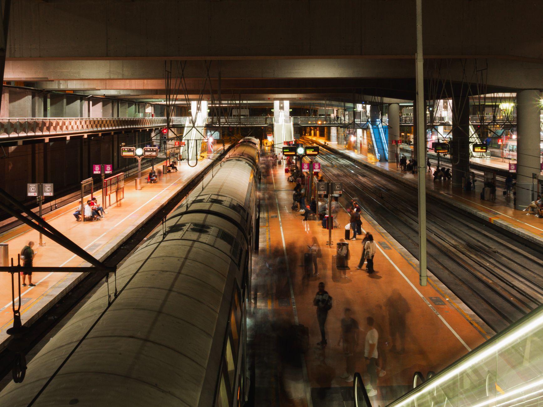 Blurred motion captures a bustling night at a Madrid railway station with people and trains. — illustrating How to Reach Other Spanish Cities by Train from Madrid