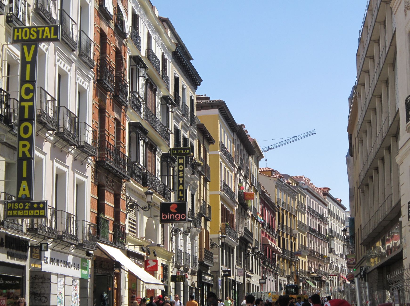 Vibrant street in Madrid showcasing classic Mediterranean architecture under a clear summer sky.