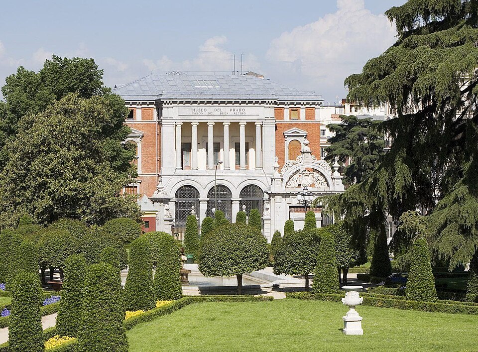 A Madrid building behind clipped formal gardens in summer