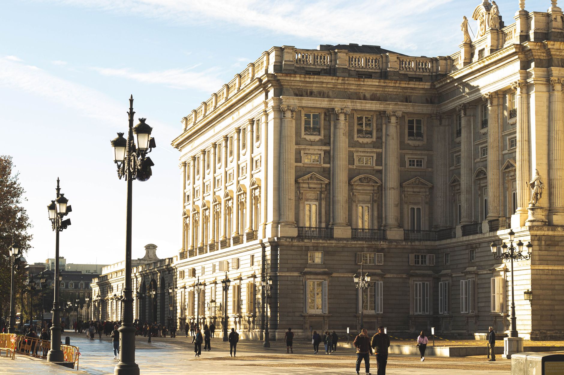 Stunning view of the Royal Palace of Madrid bathed in golden sunlight with pedestrians and classic streetlights. — illustrating What Happens to Madrid in August? A Clear Guide