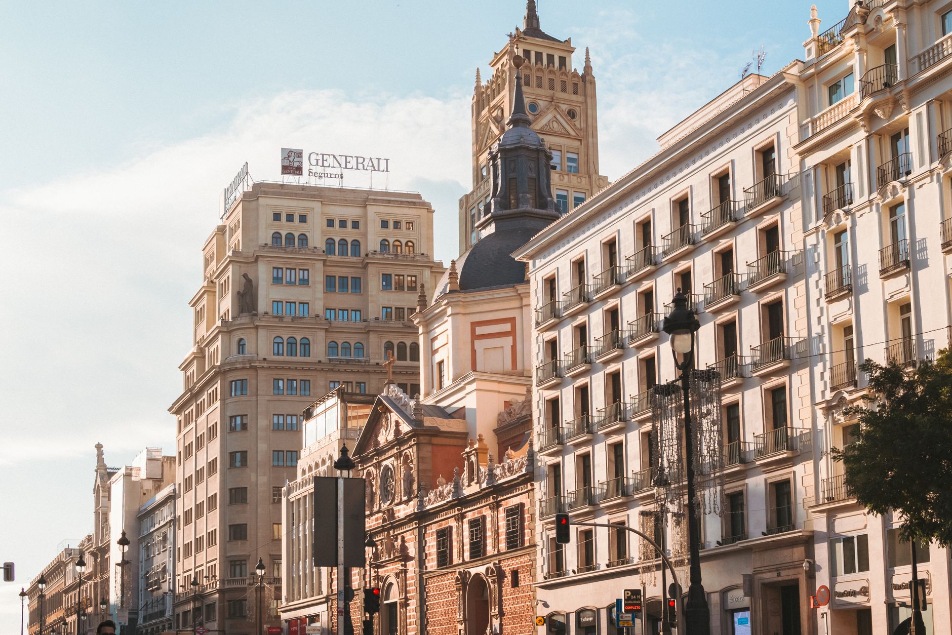 A sunny street scene in Madrid showcasing historic architecture and modern buildings